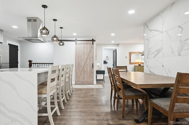 dining room featuring tile walls, dark hardwood / wood-style flooring, and a barn door