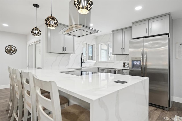 kitchen featuring black electric cooktop, dark hardwood / wood-style floors, island exhaust hood, and stainless steel fridge