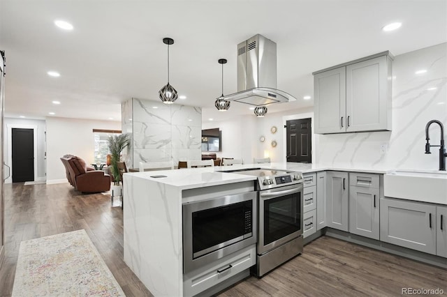 kitchen featuring island range hood, gray cabinetry, stainless steel appliances, kitchen peninsula, and sink