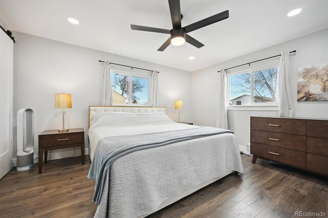 bedroom with ceiling fan, dark hardwood / wood-style floors, and a barn door