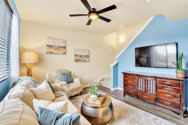 living room featuring baseboards, stairs, a ceiling fan, and wood finished floors