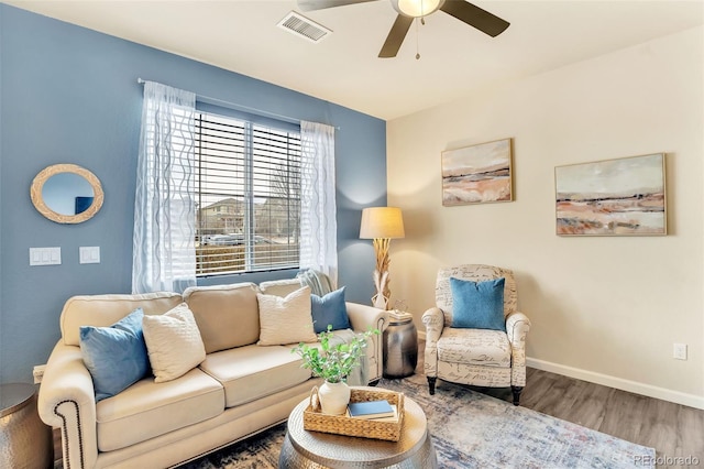 living area featuring a ceiling fan, wood finished floors, visible vents, and baseboards