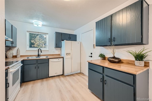 kitchen featuring wooden counters, a textured ceiling, sink, light wood-type flooring, and white appliances