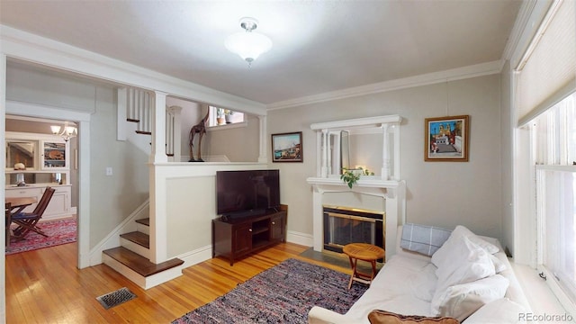 126 S Clarkson St, Denver, CO 80209 - living area featuring stairs, wood finished floors, crown molding, a fireplace with flush hearth, and a chandelier