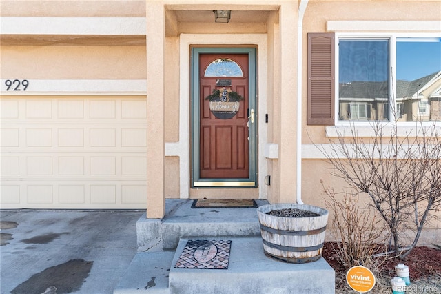 property entrance with a garage, driveway, and stucco siding