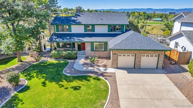 view of front of house with a front yard, a garage, a mountain view, and a porch