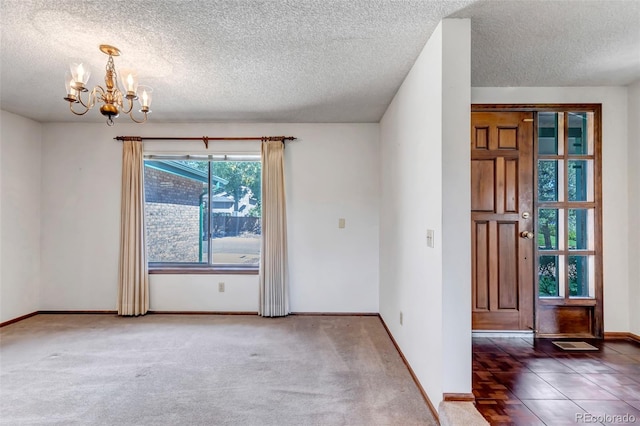 spare room with a textured ceiling, an inviting chandelier, and carpet flooring