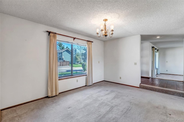 carpeted empty room with a notable chandelier and a textured ceiling