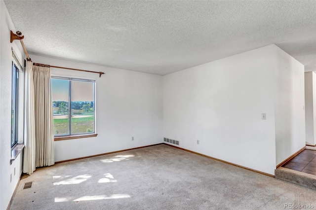 unfurnished room with a textured ceiling and carpet floors