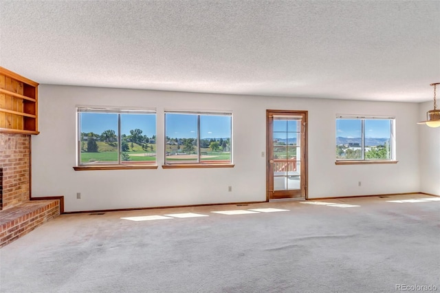 unfurnished living room with a textured ceiling, a brick fireplace, and light colored carpet