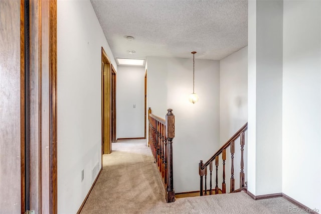 corridor featuring a textured ceiling and light colored carpet