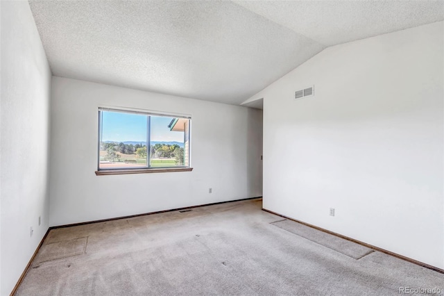 carpeted empty room featuring a textured ceiling and vaulted ceiling