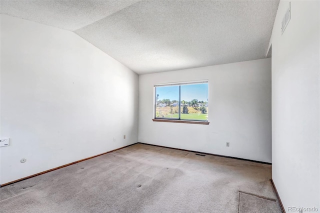 spare room featuring lofted ceiling, a textured ceiling, and light colored carpet