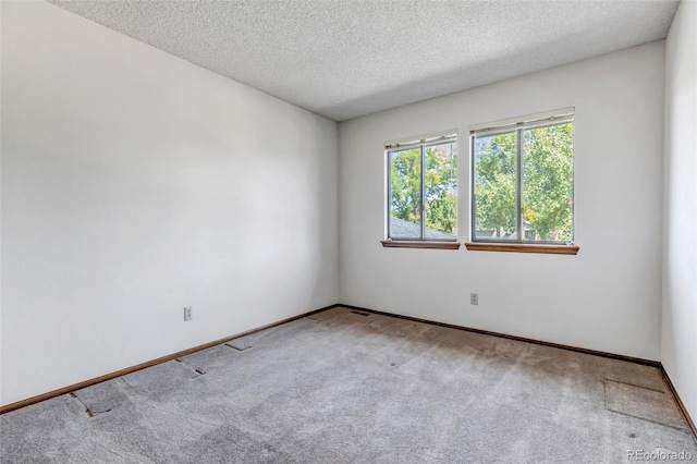 carpeted empty room featuring a textured ceiling