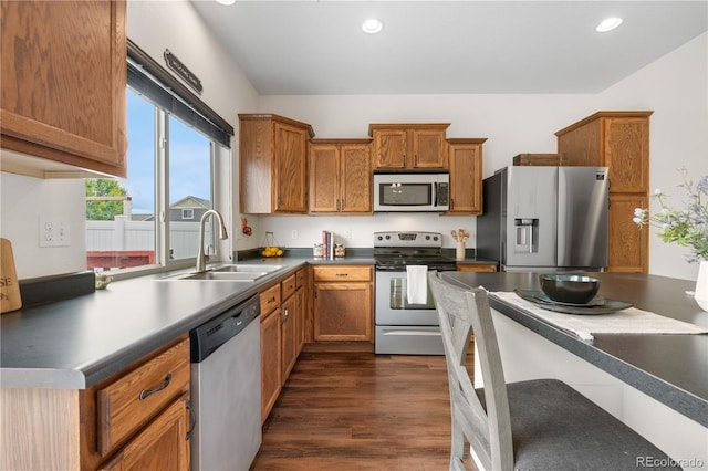 5536 Kirk St, Denver, CO 80249 - kitchen with stainless steel appliances, a sink, dark wood-style flooring, brown cabinetry, and recessed lighting