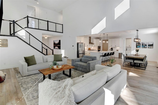 living room with a towering ceiling and light hardwood / wood-style flooring