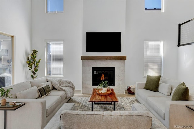 living room with hardwood / wood-style floors, a tile fireplace, and a high ceiling