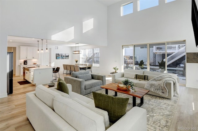 living room featuring sink, light hardwood / wood-style flooring, and a high ceiling