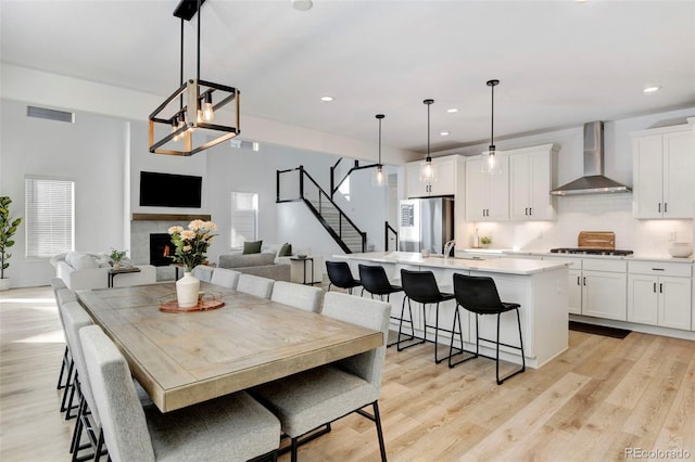 dining space featuring a tiled fireplace, sink, and light wood-type flooring