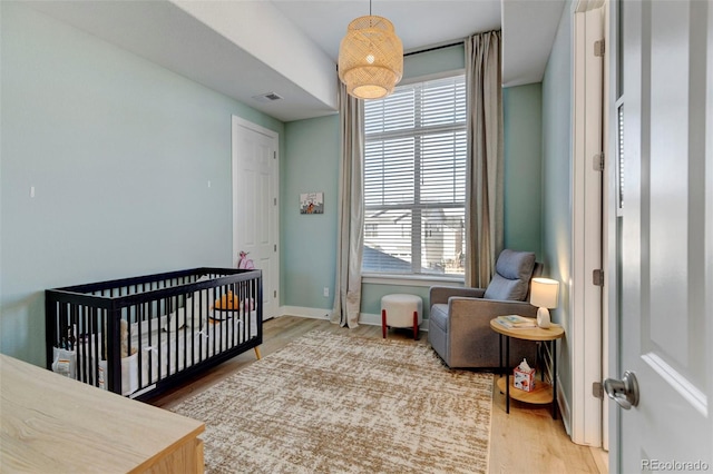 bedroom featuring multiple windows, wood-type flooring, and a nursery area