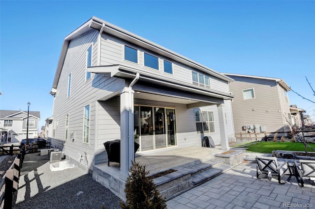 rear view of house featuring a fire pit, central AC unit, and a patio area