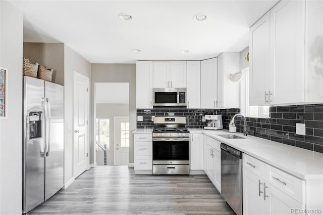 kitchen featuring sink, white cabinetry, tasteful backsplash, light hardwood / wood-style flooring, and stainless steel appliances