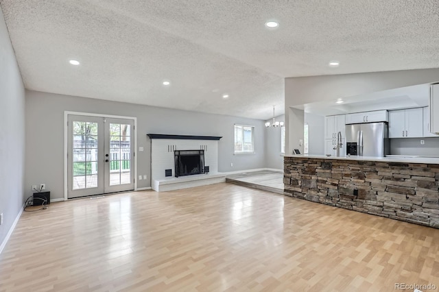 10723 Cherry Ct, Thornton, CO 80233 - unfurnished living room featuring a textured ceiling, lofted ceiling, light wood-type flooring, healthy amount of natural light, and a chandelier