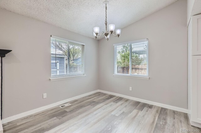 10723 Cherry Ct, Thornton, CO 80233 - unfurnished dining area with a chandelier, a textured ceiling, wood finished floors, and baseboards