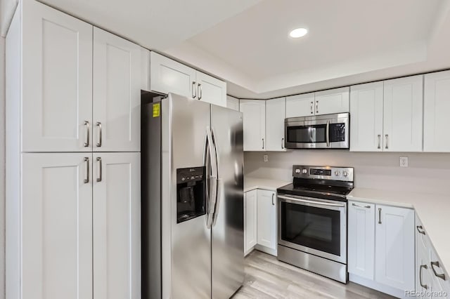 10723 Cherry Ct, Thornton, CO 80233 - kitchen featuring stainless steel appliances, light countertops, white cabinets, light wood-type flooring, and recessed lighting