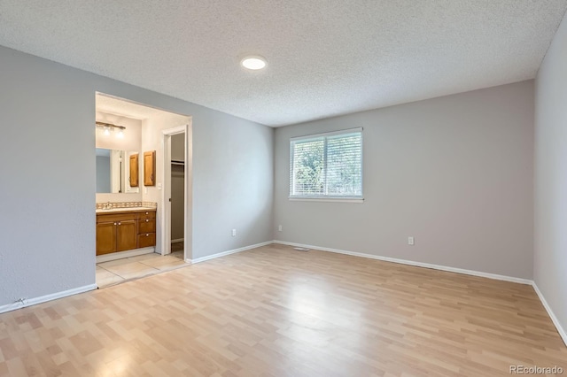 10723 Cherry Ct, Thornton, CO 80233 - unfurnished bedroom featuring light wood-style flooring, a textured ceiling, baseboards, connected bathroom, and a sink