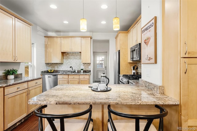 623 S Logan St, Denver, CO 80209 - kitchen featuring light brown cabinets, appliances with stainless steel finishes, a peninsula, light stone counters, and tasteful backsplash