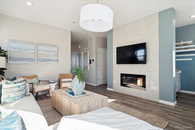 living area featuring wood finished floors, visible vents, recessed lighting, baseboards, and a tile fireplace