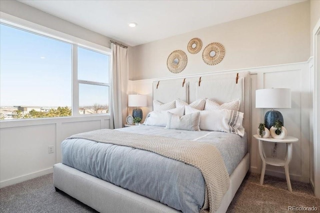 carpeted bedroom with a decorative wall and wainscoting