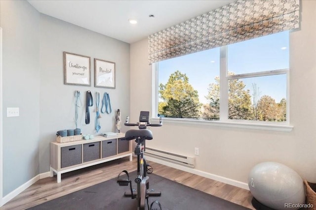 exercise room with baseboards, a baseboard radiator, and wood finished floors