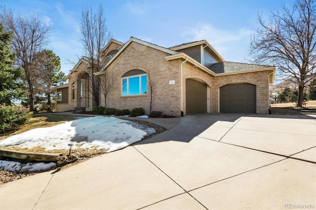 view of front of home featuring a garage, concrete driveway, and brick siding