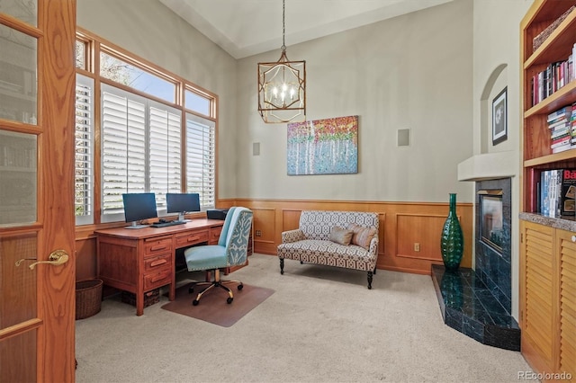 office area featuring carpet, a wainscoted wall, a fireplace, and an inviting chandelier