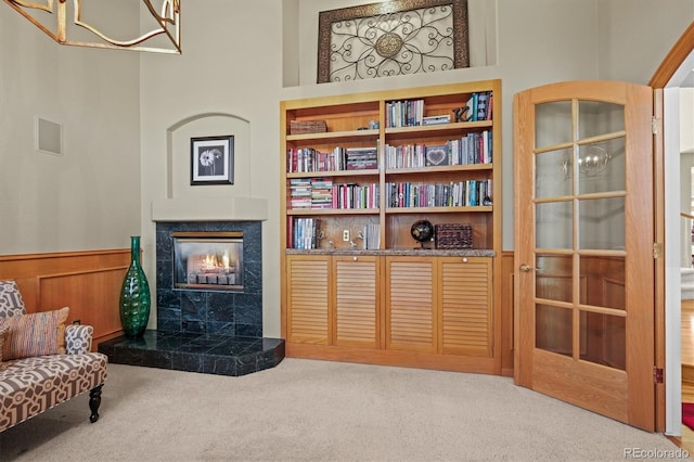 living area featuring carpet floors, wainscoting, a fireplace, and built in features