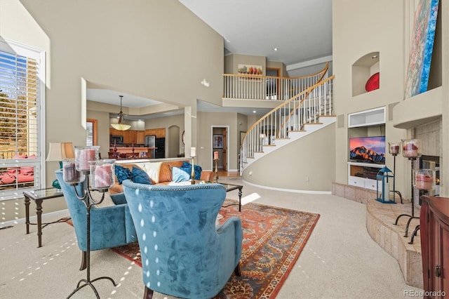 living room with a towering ceiling, carpet, stairs, and baseboards