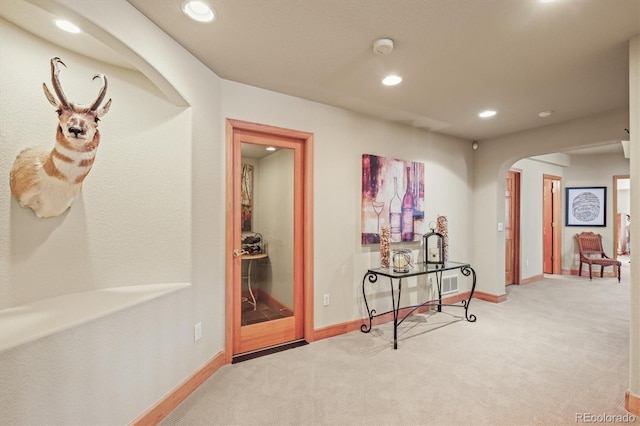 hall featuring carpet floors, baseboards, arched walkways, and recessed lighting