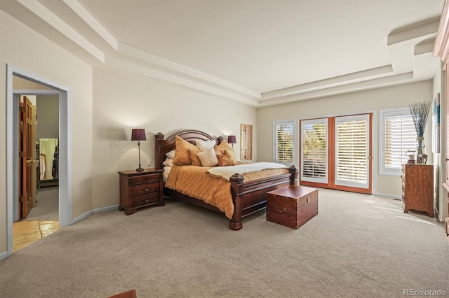 carpeted bedroom with a tray ceiling, access to outside, and baseboards