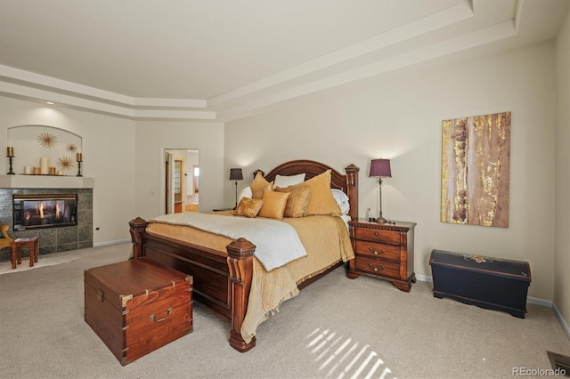 bedroom with baseboards, ensuite bath, a tray ceiling, carpet floors, and a fireplace