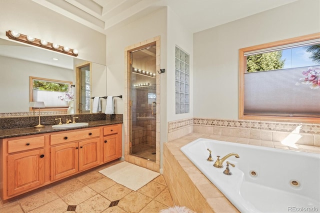 bathroom featuring plenty of natural light, a shower stall, vanity, and a tub with jets