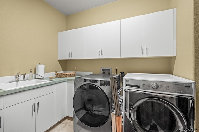 laundry area featuring cabinet space, light tile patterned floors, a sink, and washing machine and clothes dryer