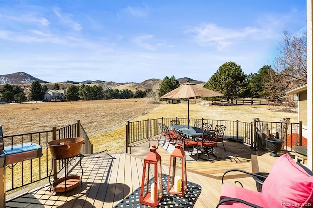 wooden deck with a rural view, a mountain view, and outdoor dining space