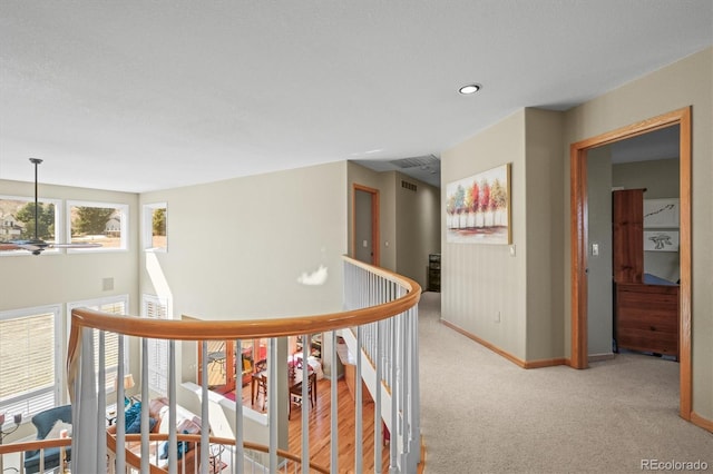 hallway with visible vents, carpet, an upstairs landing, and baseboards