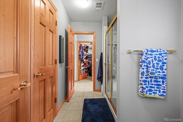 hall featuring light tile patterned flooring, visible vents, and baseboards