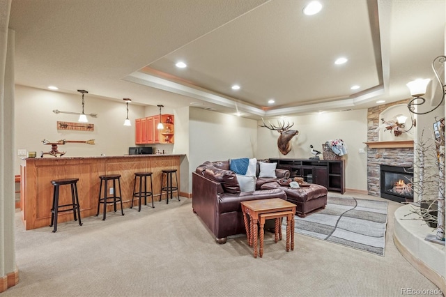 living area with indoor wet bar, a raised ceiling, light carpet, and a fireplace