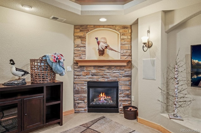 carpeted living area with a textured wall, a fireplace, visible vents, and baseboards