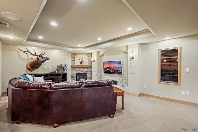 living room with light carpet, a stone fireplace, a raised ceiling, and baseboards