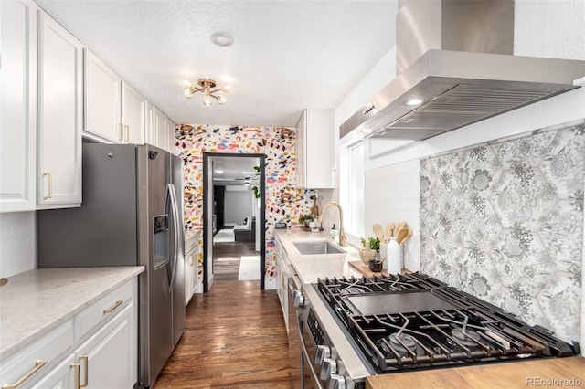 1946 Xenia St, Denver, CO 80220 - kitchen with wall chimney range hood, appliances with stainless steel finishes, white cabinets, dark wood finished floors, and decorative backsplash